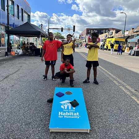 Kids playing Habitat-branded bean bag toss at an event.