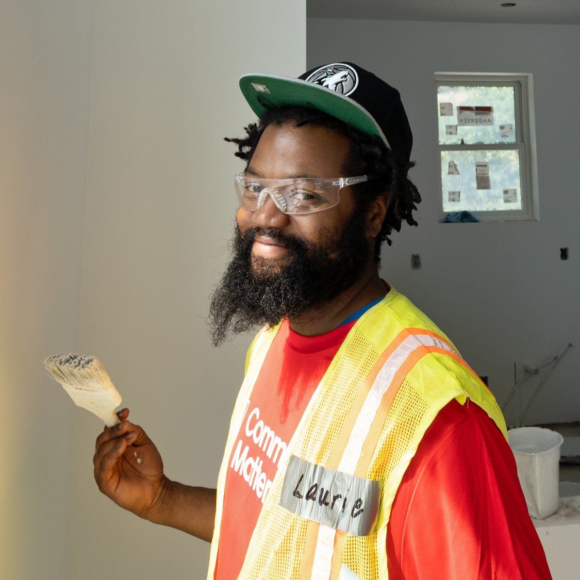 Volunteer smiling and holding a paintbrush.