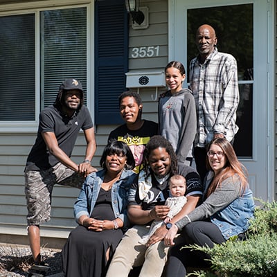 Angela with her family in front of her home.