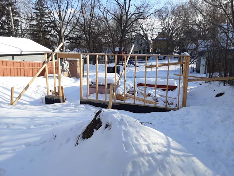 A framed garage in a yard of snow.