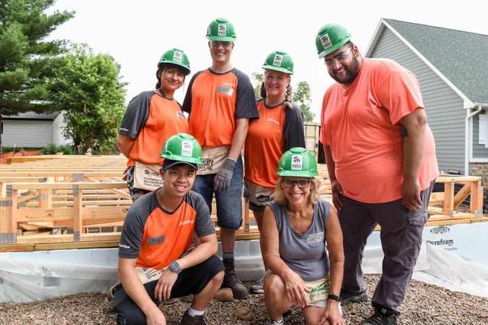 Group of construction volunteers posing on a build site.