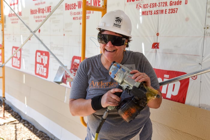 Construction volunteer in a hard hat and holding a power drill.