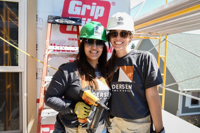 Two volunteers wearing Andersen shirts and hard hats.