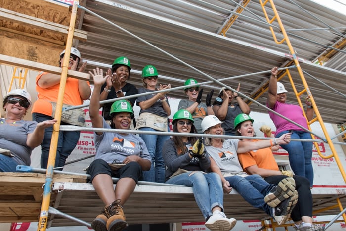 Group shot of volunteers sitting and standing on scaffolding.