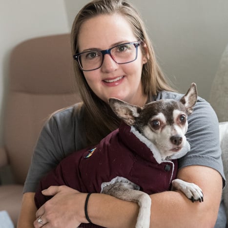 A woman smiling and holding her dog